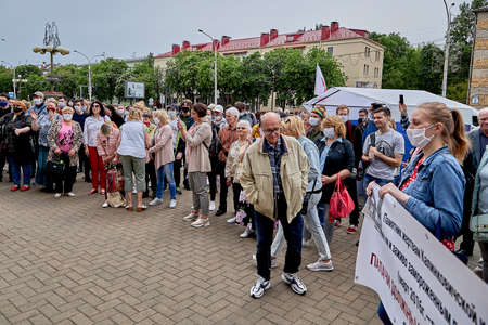 June 7 2020 Minsk Many masked people with a large placard stand during a protest in the city square. A man reads the inscription on the posterのeditorial素材