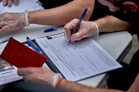 June 7 2020 Minsk Belarus Close-up of a masked man filling out a presidential candidate's signature sheetのeditorial素材