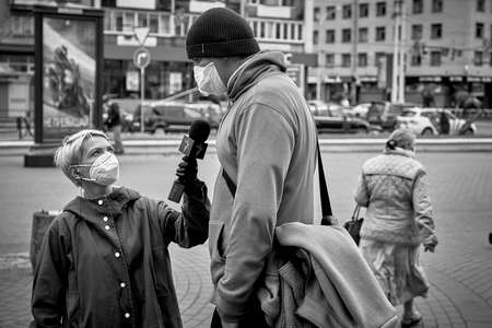 June 14 2020 Minsk Belarus Black-and-white close-up image of a masked female reporter with a microphone talking to a tall masked man on the street.のeditorial素材