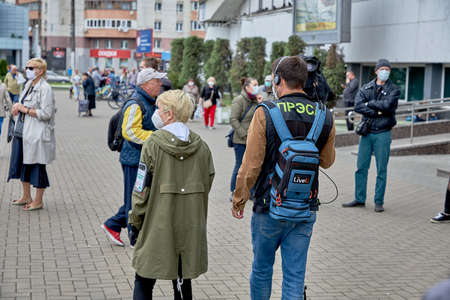 June 14 2020 Minsk Belarus A masked woman and a man with a large camera walk down the street among masked peopleのeditorial素材