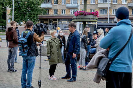 June 14 2020 Minsk Belarus A masked female reporter with a microphone interviews a man on the streetのeditorial素材