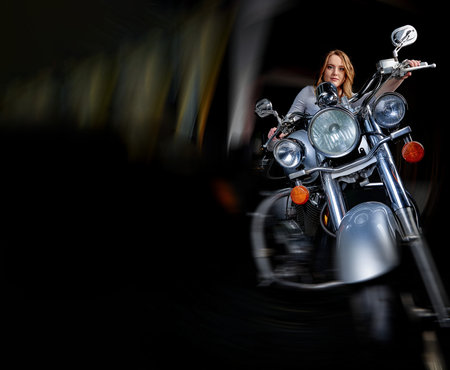 A woman rides a motorcycle through the streetsの写真素材