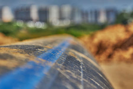 A plastic water pipe lies on the ground against the background of the city in the distanceの写真素材