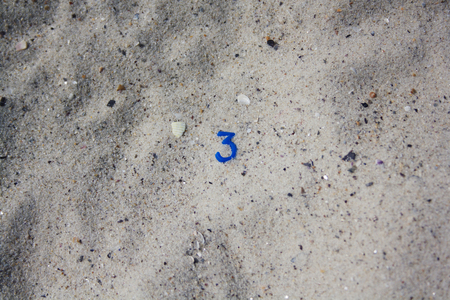 Tiny number three in the sand.  Hipster styleの写真素材