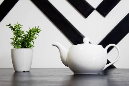 kettle and plant in a flowerpot on the table in the interiorの写真素材