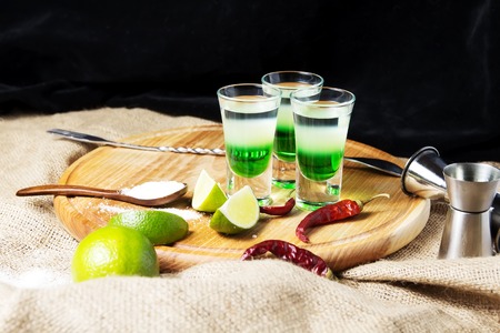 three alcoholic drinks shot on a wooden board with fruitの写真素材