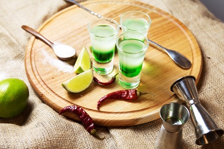 three alcoholic drinks shot on a wooden board with fruitの写真素材