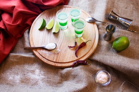three alcoholic drinks shot on a wooden board with fruitの写真素材