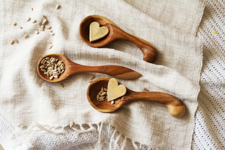 Wooden spoons hand on the table. Composition of wooden spoons on a drapery spilling seeds. Spoons from apricot wood.の写真素材