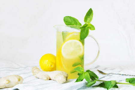 Lemonade with ginger and mint in kitchen. Home made ginger lemonade on striped napkin or towel. Healthy drink lemonade.の写真素材