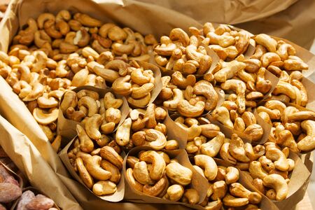 Roasted cashew in paper envelope food festival. Background, pattern of cashew. Nuts on street food...
