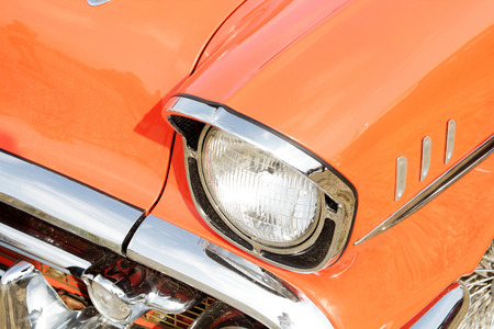 Orange vintage car on a festival of old cars. Retro car's headlight close up.
