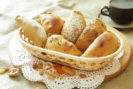 Russian pirozhki, baked patties or pies on basket with nuts and dried apricots