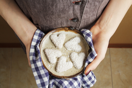 hands holding ceramic plate with biscuits in the shape of a heart, St.Valentine's Day concept. Preparaing food.の写真素材