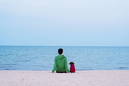 Young woman and dog looking to the sea dressed in the same clothes