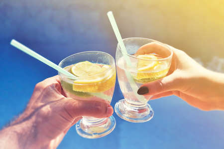 Young couple with drinks at the swimming pool.の写真素材