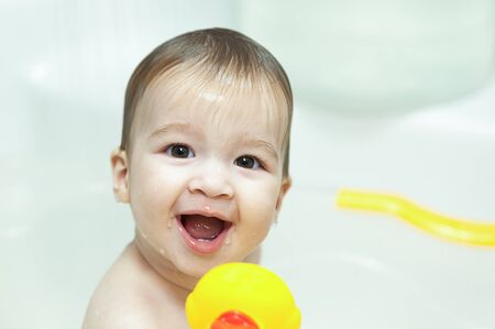 Nine months baby girl in the bathroom with her yellow duckの写真素材