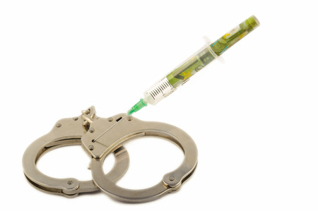 Isolated injection shot with money on the handcuffs over whiteの写真素材