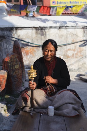 KATHMANDU, NEPAL - NOVEMBER 26, 2011: Old Tibetan buddhist lady prayer rosary at Baudhanath Temple. As of 1979, Boudhanath is a UNESCO World Heritage Site. Along with Swayambhunath, it is one of the most popular tourist sites in the Kathmandu areaのeditorial素材