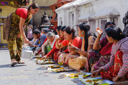 KATHMANDU, NEPAL - JULY 09, 2011: People having food at open wedding breakfast in Swayambhunath temple garden. Swoyambhunath is an ancient religious complex atop a hill in the Kathmandu Valley, west of Kathmandu city. It is also known as the Monkey Templeのeditorial素材