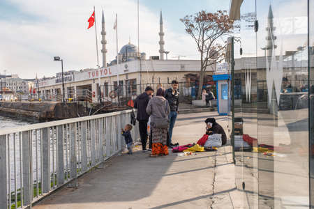 Eminonu, Istanbul, Turkey - 02.18.2021: a refugee family gathering together and mother talking on phone and kid looking at sea under Turkish flag and mosques with copy spaceのeditorial素材