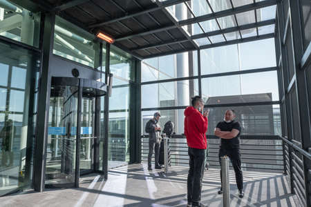 Arnavutkoy, Istanbul, Turkey - 03.08.2021: smoking lounge in Istanbul Airport and some people with mask smoke cigarettes in front of ashtrays in daylight before getting on a planeのeditorial素材