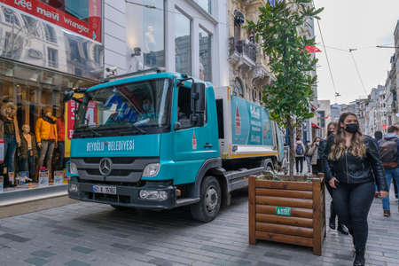 Beyoglu, Istanbul, Turkey - 03.12.2021: blue municipality garbage truck parked on Istiklal Street and people with mask walking around with copy spaceのeditorial素材