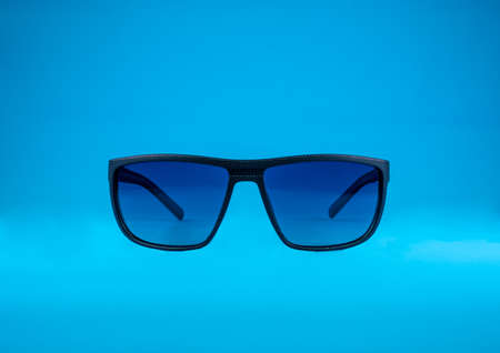 Sun Glasses with blue glass and black frame on blue background