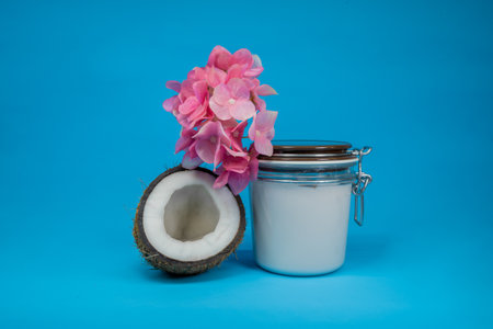 White jar of coconut batter with coconut, cosmetic product on blue background. Minimal concept. Showcase for presentation skincare productsの写真素材
