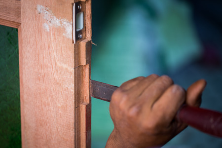 Close up carpenter's hands that work with cutterの写真素材
