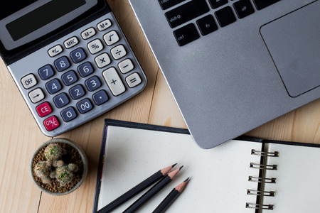 View from above on the office working place at morning. Well organized workspace on the wooden table with laptop, pencils,pot of cactus and other business suppliesの写真素材