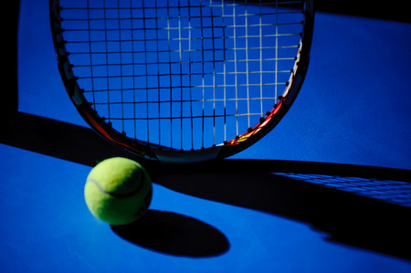 tennis racket and tennis ball put on blue courtの写真素材