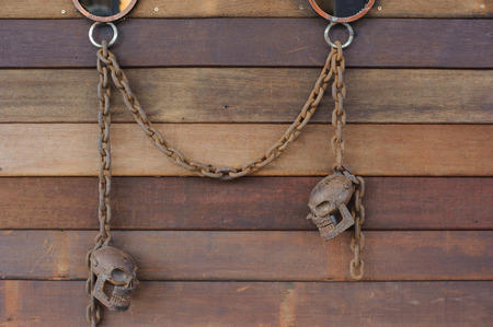rusty skull with rust chain hang on the wood wallの写真素材