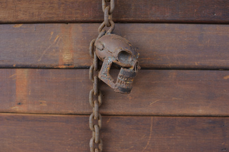 rusty skull with rust chain hang on the wood wallの写真素材