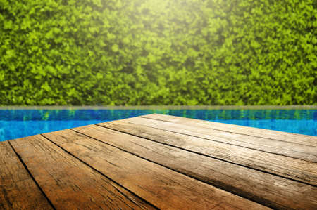 Wooden table in front with empty space for advertise display and blurred background of swimming pool...