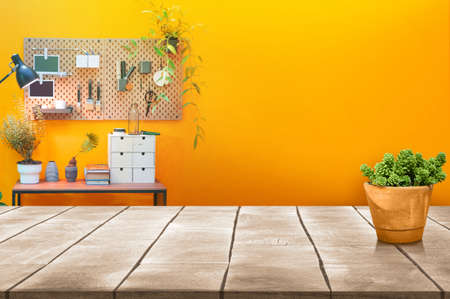 Wooden table top and tree pot with paintbrush tool on board hanging on the yellow wall