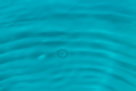 water drop splash in a glass blue coloredの写真素材