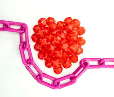 candies as heart shaped candy on white background, concept love or relationship, purple chain around candy heartsの写真素材