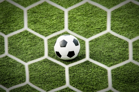 Soccer football in net with green grass field の写真素材