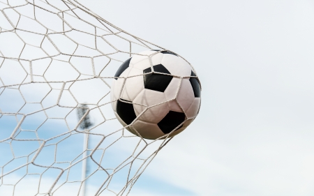 Soccer football in Goal net with sky field の写真素材