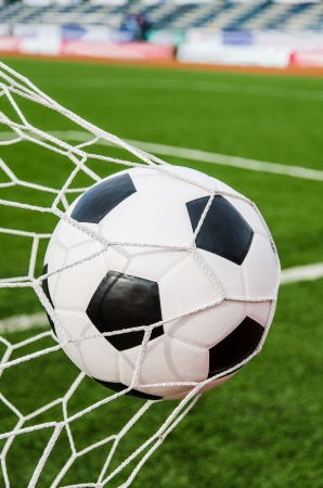 Soccer football in Goal net with green grass field の写真素材