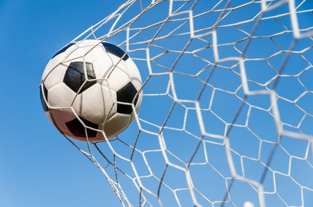 Soccer football in Goal net with sky field の写真素材