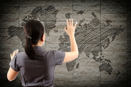 Business Lady touching world map drawing on the wall の写真素材