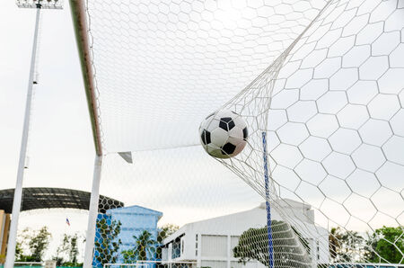Soccer football in Goal net with the sky field 