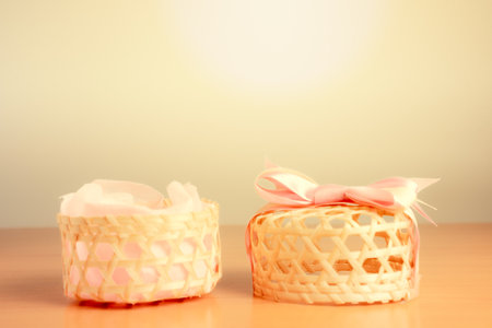 wicker basket with ribbon on wood table and light background - vintage filterの写真素材