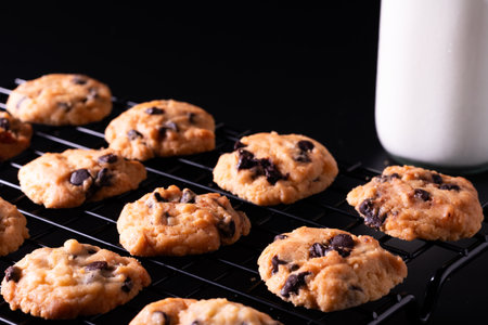 Chocolate chip cookies on a cooling rack with a glass of milk
