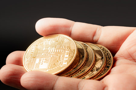 Golden bitcoin in human hand on black background. Cryptocurrency concept