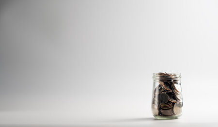 Coins in a glass jar on a white background with copy spaceの写真素材