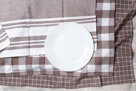 A wooden vintage Table or background with a dish towel and plate, top viewの写真素材