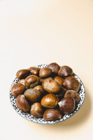 A minimalistic photo of a vintage bowl of chestnuts on beige backgroundの写真素材
